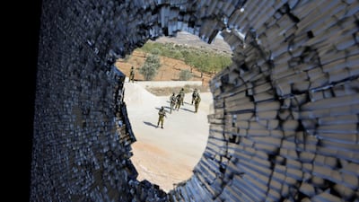 Israeli troops wait outside a Palestinian home damaged by settlers in the occupied West Bank. Reuters