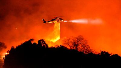In this photo released by the Santa Barbara County Fire Department , a Los Angeles County Firehawk copter makes a water drop on flames off California Highway 154. AFP