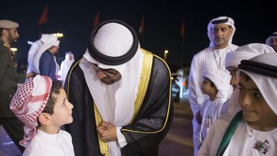 Sheikh Mohammed bin Zayed, Crown Prince of Abu Dhabi Deputy Supreme Commander of the Armed Forces (C) greets a young guest during the 44th UAE National Day celebrations at Zayed Sports City. Mohamed Al Hammadi / Crown Prince Court - Abu Dhabi