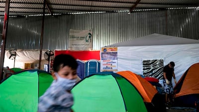 An asylum seeker stands next to a tent for COVID-19 suspects (background) as a child plays, at the Juventud 2000 migrant shelter in Tijuana, Baja California state, Mexico. Thousands of asylum seekers wait in Mexico for the US Departments of Justice and Homeland Security to resume the migration hearings after they were suspended due to the COVID-19 pandemic. The World Refugee Day is commemorated on June 20. AFP