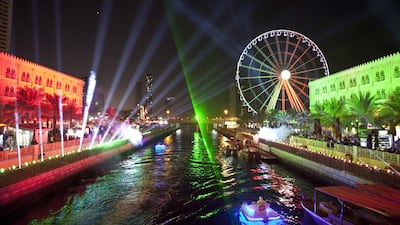 Families watch a light show at Qanat Al Qasba near the Corniche yesterday, one of a series of celebrations organised ahead of today’s National Day festivities. Parades and music also delighted residents. Antonie Robertson / The National