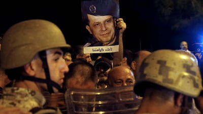 A supporter of Lebanese President Michel Aoun holds up his picture with Arabic that read "Because you are our dignity," as Lebanese republican guards stand guard during a protest near the presidential palace in the Beirut suburb of Baabda, Lebanon. AP Photo