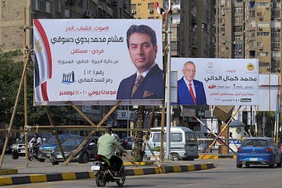 Motorists drive past campaign billboard for Egyptian Parliamentary election candidates in the greater Cairo area. AFP