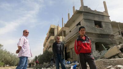 Syrians stand in front of heavily damaged buildings on April 8, 2016 in Al Qaryatain, a few days after Syrian regime forces seized it from ISIL. AFP / Max DELANY