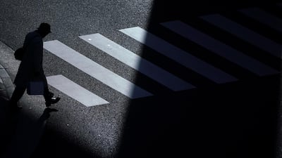 A man walks across a street in a cold winter evening in Tokyo. Eugene Hoshiko / AP Photo