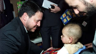 The Jordanian King chats to a child at the cancer centre in Amman in January 2002. AFP