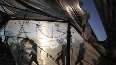 Palestinian men walk behind a greenhouse damaged by an Israeli airstrike launched in response to rocket fire, in Khan Yunis in the southern Gaza Strip on November 2, 2019. AFP