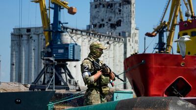 A Russian soldier guards a grain storage area at Mariupol's sea port, which has reopened after heavy fighting. Russia's blockade of Ukrainian ports is leading to shortages and increased hunger around the world. AP