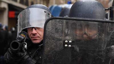 Riot police prepare to shoot a tear gas canister near the Arc de Triomphe in Paris on December 8, 2018. AFP