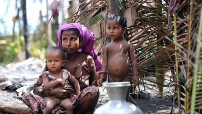 A Rohingya Muslim woman sits with her children outside a temporary shelter at a village in Minpyar in Rakhine state. Homeless people fled to packed camps or clustered near their charred houses amid ongoing unrest.