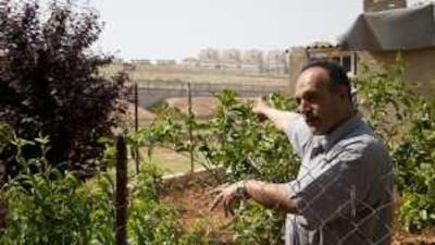 Salah Assaf points out the Israeli separation barrier and, behind that, the Givat Zeev settlement.