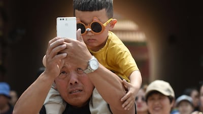 A man takes a selfie with a young boy after visiting the Forbidden City in Beijing. AFP