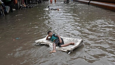 Children float along a waterlogged street after heavy monsoon rain in Kolkata, India. AFP