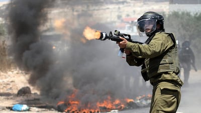 An Israeli border policeman fires teargas towards Palestinian demonstrators during a protest against the expansion of the nearby Jewish settlement of Kdumim, in the northern West Bank village of Kufr Qaddum, Friday, July 6, 2012. (AP Photo/Nasser Ishtayeh)