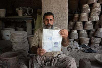 Shirin Agha, 45, poses for a picture as he holds his id card or Tazkira registered to vote in the upcoming parliamentary election at his workshop, on the outskirts of Jalalabad. AFP