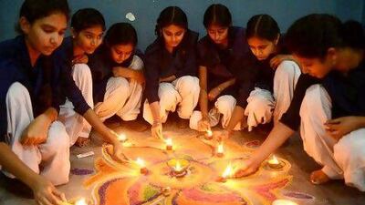 Indian schoolgirls light candles as they sit near a 'Rangoli', made from coloured powder during pre-Diwali celebrations at school in Amritsar.