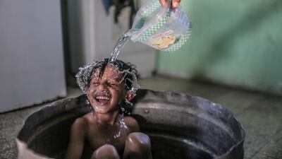 A woman washes her son in their house on the outskirts of Khan Younis refugee camp, Gaza Strip.