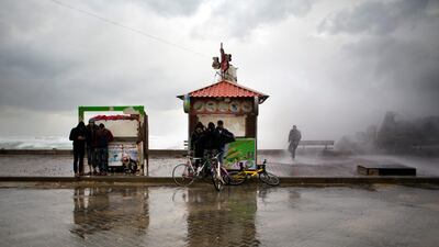 Palestinians take a cover from wind and rain on the Mediterranean seaside, in Gaza City. AP Photo
