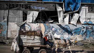 A Palestinian man on a donkey cart passes by a partially destroyed soft drink factory following Israeli airstrikes on Gaza City. AP Photo