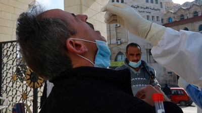 A member of the Jordanian health ministry's epidemiological investigation team, takes a random nasal swab to test for Covid-19, from a man leaving the King Abdullah I mosque following the Friday noon prayers, in the capital Amman, on December 18, 2020. AFP
