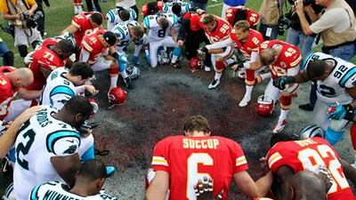 Members of the Kansas City Chiefs and Carolina Panthers sides pray together after their match.