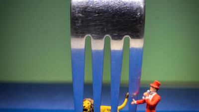 A circus master rounds up his lion behind cage bars made by the prongs of a fork. The image is captioned as "Lion In a Cage". Courtesy Omar Maree Humaid