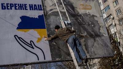 A worker sets up a billboard with the colours of the Ukrainian flag in Novoiavorisk, near Lviv. AP
