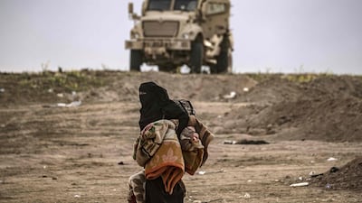 A Syrian woman walks past a military vehicle as hundreds of civilians, who streamed out of the Islamic State group's last Syrian stronghold, headed towards a screening point run by the Syrian Democratic Forces, outside Baghouz. AFP/Delil Souleiman