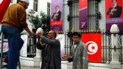 Workers put up banners backing the Tunisian president, Zine el Abidine Ben Ali, in today's elections.