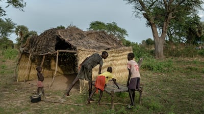 Akech, 9, is helped by her older brothers settling in to the new shelter they built in Langic.