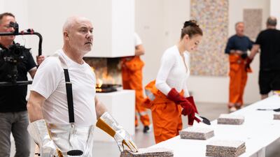 The artist was dressed in silver metallic boiler-suit trousers and matching fire safety gloves as he collected each piece and burned it in a contained fire box. Getty Images