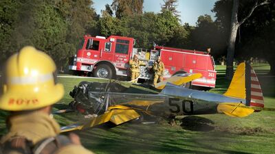 Firefighters stand before the small plane owned by US actor Harrison Ford after crashing at the Penmar Golf Course in Venice, California. Jonatahn Alcorn / AFP Photo