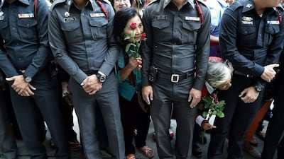 Supporters former Thai prime minister Yingluck Shinawatra hold roses as they wait for her to arrive for a hearing at the supreme court in Bangkok. Christophe Archambault / AFP Photo