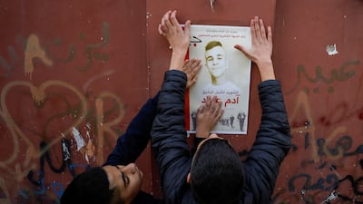Boys put up a poster of Palestinian teenager Adam Ayyad, who medics said was killed by Israeli forces. Reuters