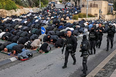 Israeli security forces walk past Muslim worshippers praying near the Old City walls. AFP