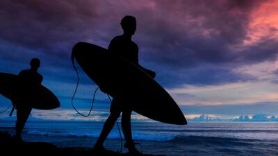 Indonesian men walk with their surf boards at sunset on Tapaktuan beach, Southern Aceh province. AFP
