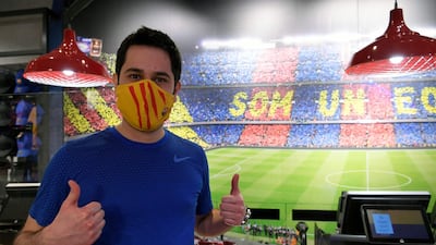 A supporter poses wearing a mask bearing the logo of FC Barcelona after buying it at the FC Barcelona store. AFP
