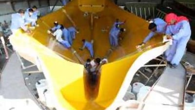 Workers polish the inside surfaces of a dhow under construction at Al Boom Marine in Ajman.