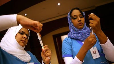 Fatima al Shameri, left, and Mona Abdul Rahman, both nurses with an Abu Dhabi health provider, prepare swine flu vaccines at the Emirates Center for Studies and Strategic Research in the capital.