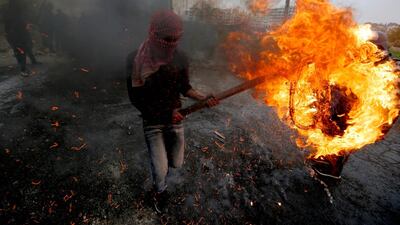 A Palestinian man carries a burning tyre during clashes with Israeli forces. AFP