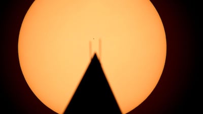 A handout photo made available by NASA, showing the the planet Mercury seen in silhouette, centre, as it transits across the face of the Sun, behind the Washington Monument. Mercury's last transit was in 2016. The next transit will not happen again until 2032. EPA