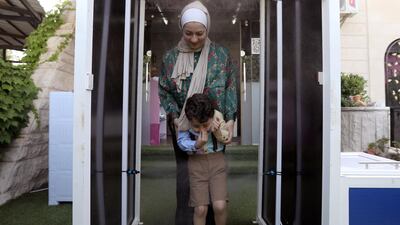 A woman and her child are sprayed with disinfectant as they enter a nursery after the government eased the coronavirus restrictions in Amman, Jordan. Reuters