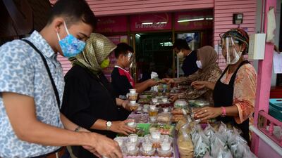People wearing face masks buy food at a market in Thailand's southern Narathiwat province. AFP