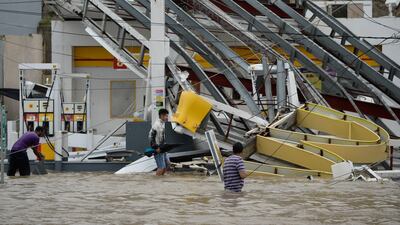 People walk next to a gas station flooded and damaged by the impact of Hurricane Maria, which hit the eastern region of the island, in Humacao, Puerto Rico. Carlos Giusti / AP Photo
