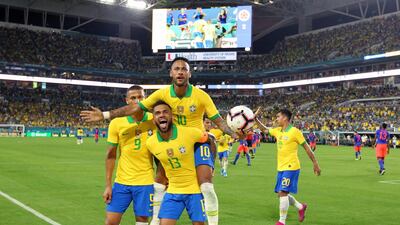 Neymar (10) celebrates with Dani Alves (13) and Richarlison (9) after scoring the second goal. Miami Herald via AP