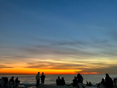 Families and groups of friends perch on plastic chairs to watch the sunset