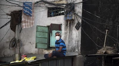A man wearing facemask sits on a roof at the Dharavi slum in Mumbai. AFP