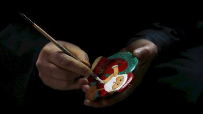 Kashmiri artisan Syed Maqbool paints a papier mache Santa Claus at a workshop in Srinagar, the summer capital of Indian Kashmir. EPA