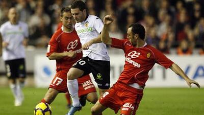 Valencia's Juan Manuel Mata, centre, is tackled by Mallorca's Ivan Ramis, right, at the Mestalla.