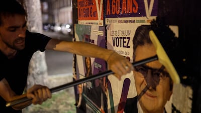 In Strasbourg, eastern France, a supporter of hard-left leader Jean-Luc Melenchon pastes an electoral poster ahead of the second round of the legislative elections. AP